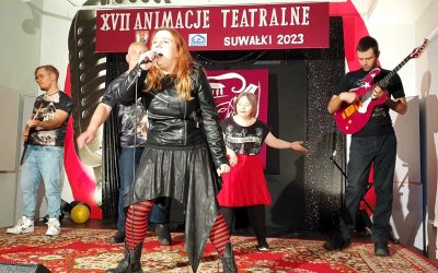 Kobieta na scenie śpiewa wraz z zespołem
